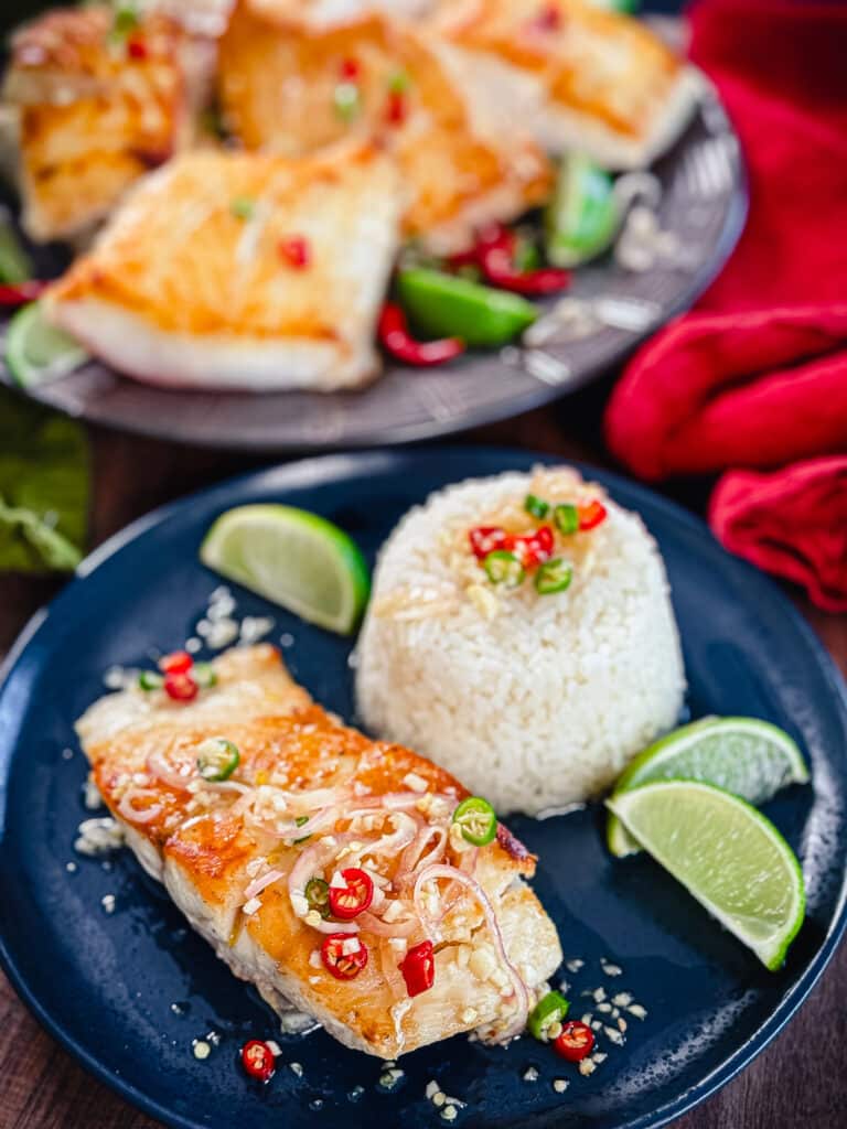 red snapper with prik nam pla on a blue plate with rice and limes