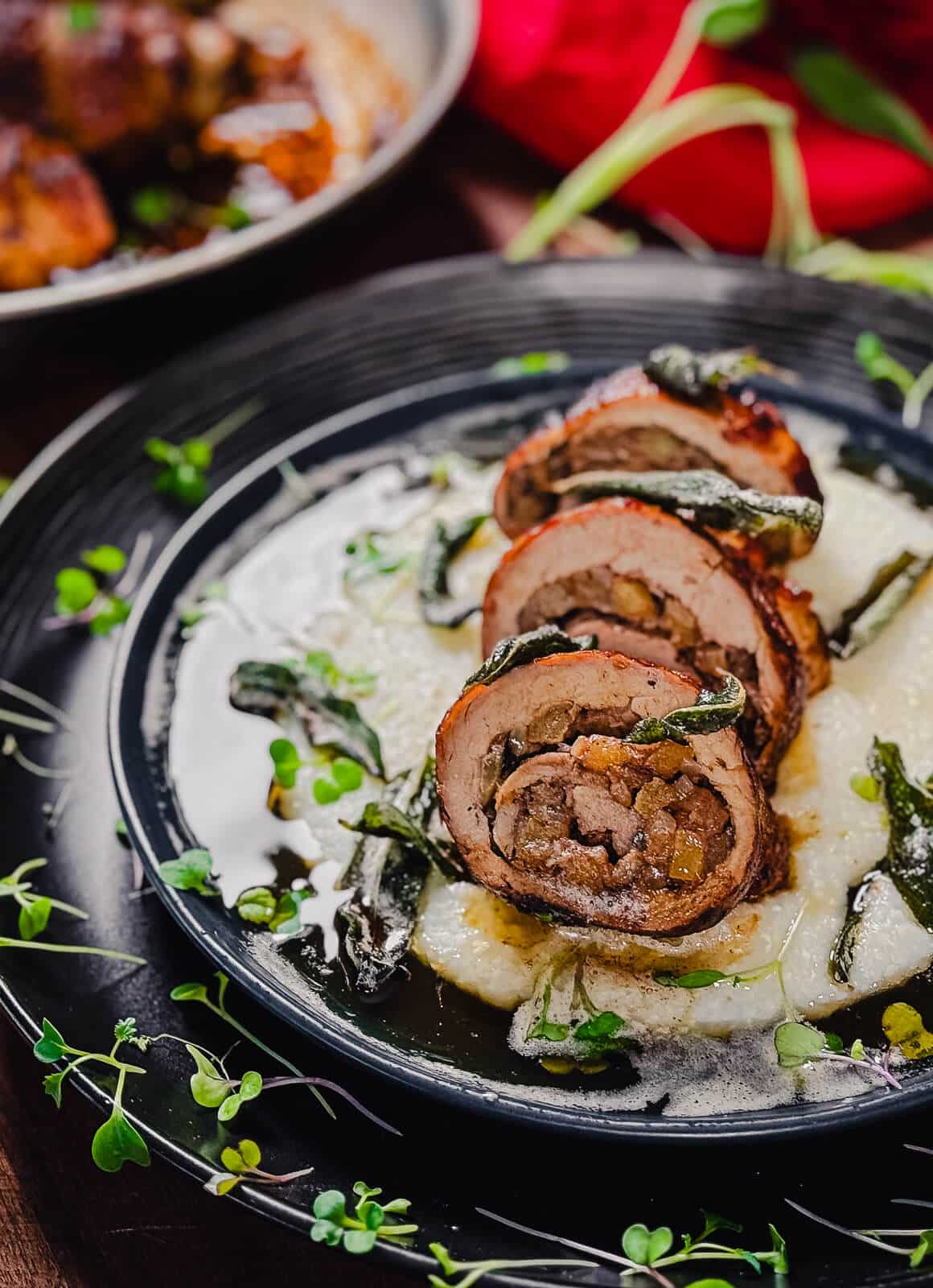 sliced stuffed pork tenderloin on a blue plate with herbs