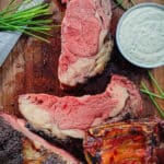 smoked prime rib roast on a cutting board with chives and horseradish sauce