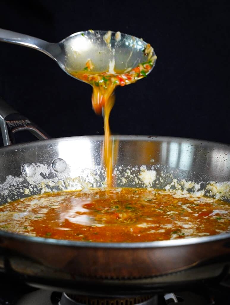 calabrian chili butter dripping off of a spoon into a pan