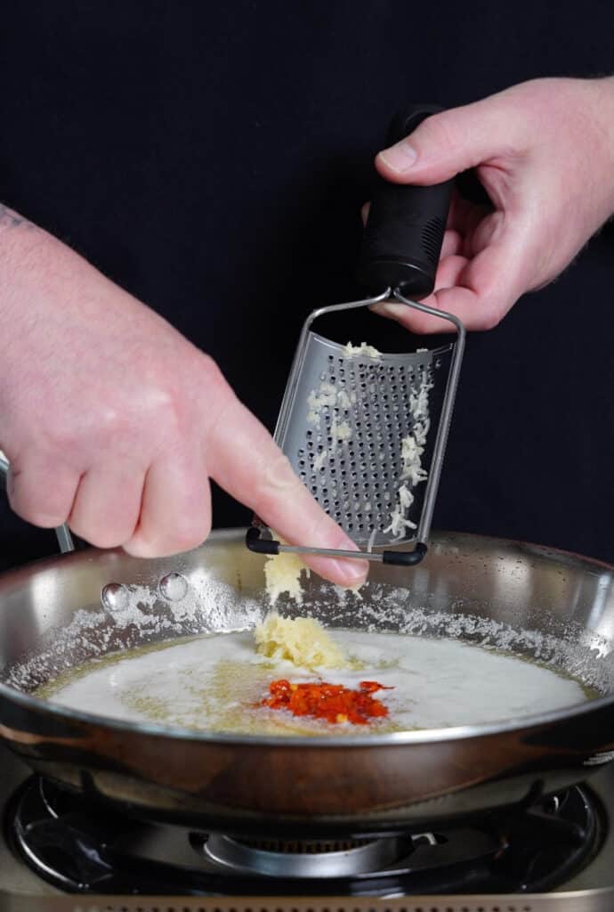 grated garlic being added to melted butter