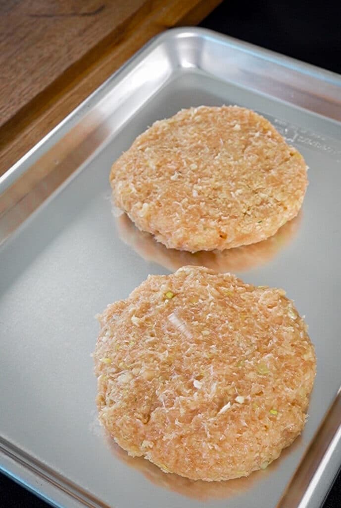 uncooked ground chicken patties sitting on a baking sheet