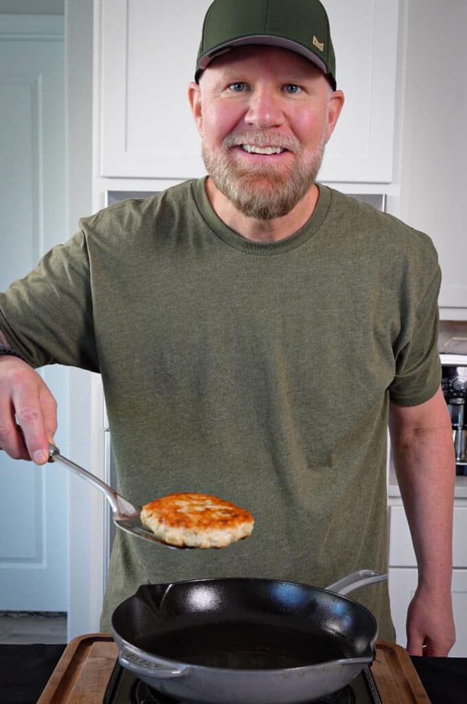 seared chicken patty on a spatula over a cast iron pan