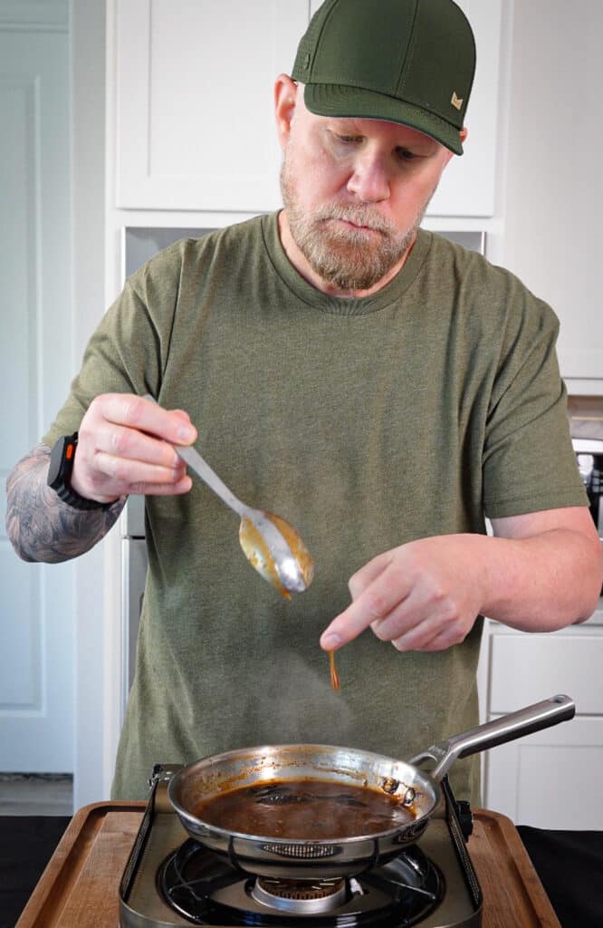 kung pao sauce clinging to the back of a spoon over a pan