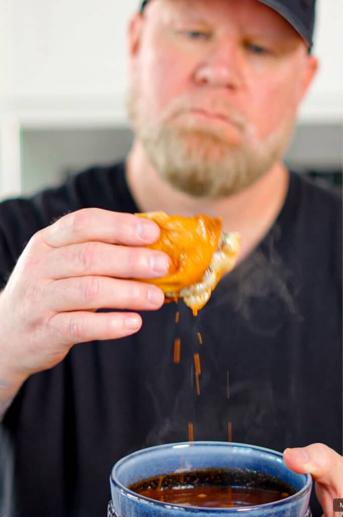 man in black tee shirt eating  a birria smashburger