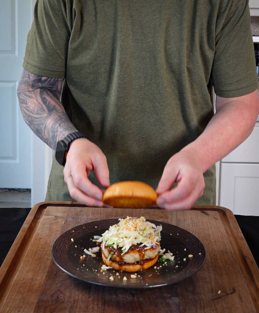top bun being added to a kung pao chicken burger