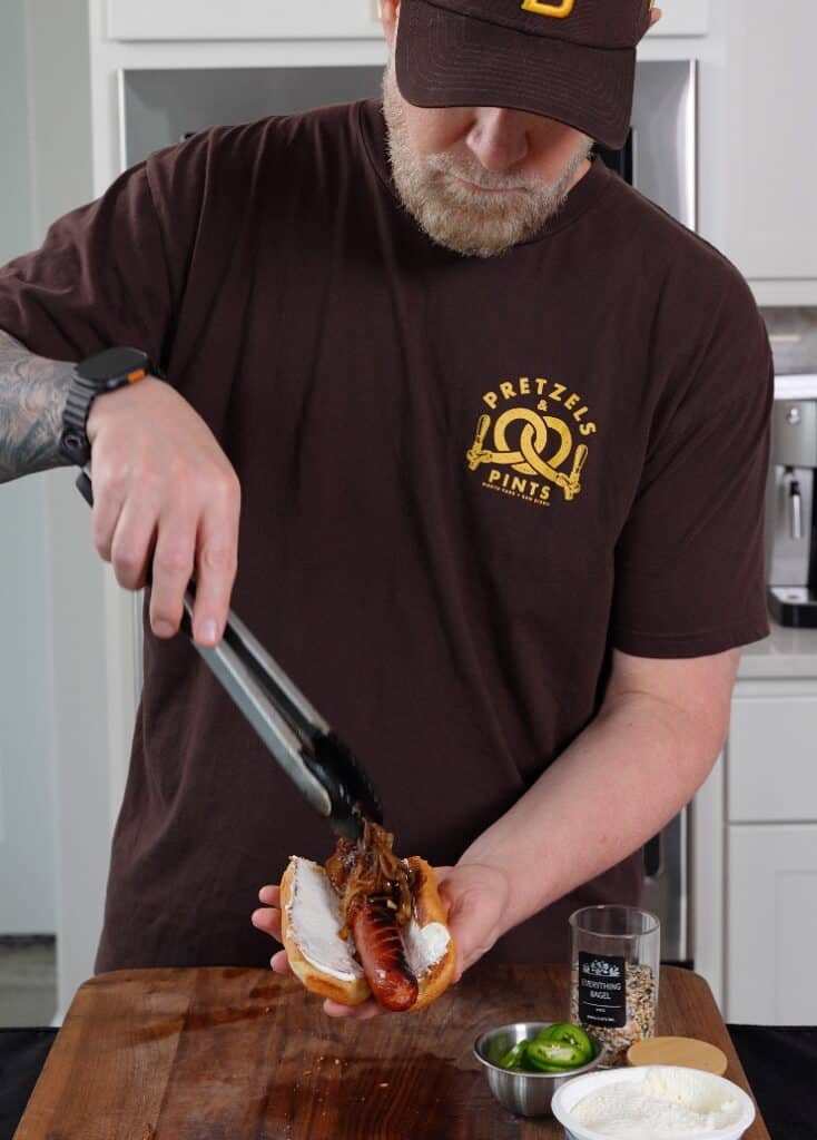 caramelized onions being added to a hot dog