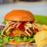 venison burger with bacon and cheery bbq sauce on a plate with potato chips