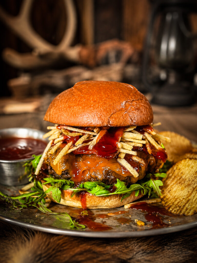 venison burger topped with shoe string potatoes, melted cheddar cheese and cherry bbq sauce