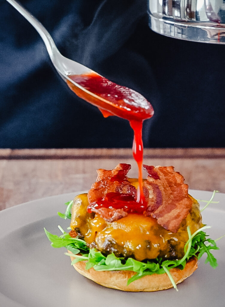 cherry BBQ sauce being drizzled on a venison burger
