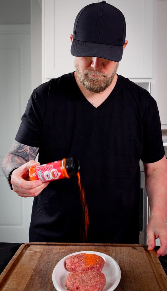 seasoning being added to a venison burger patty