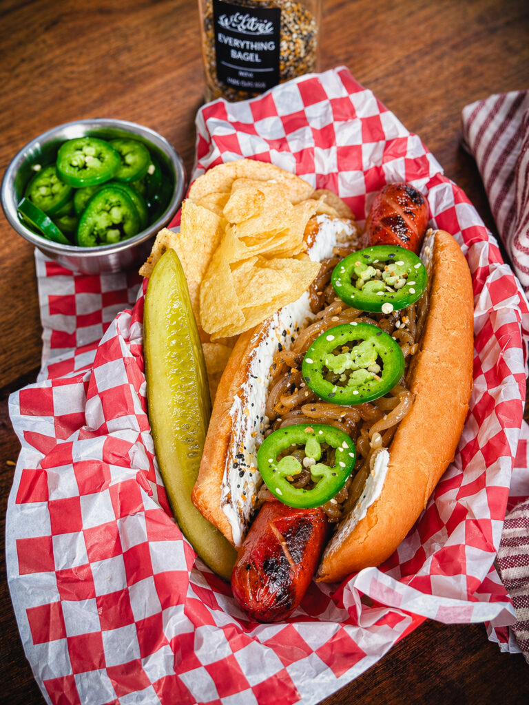 seattle style hot dog in a serving tray with potato chips
