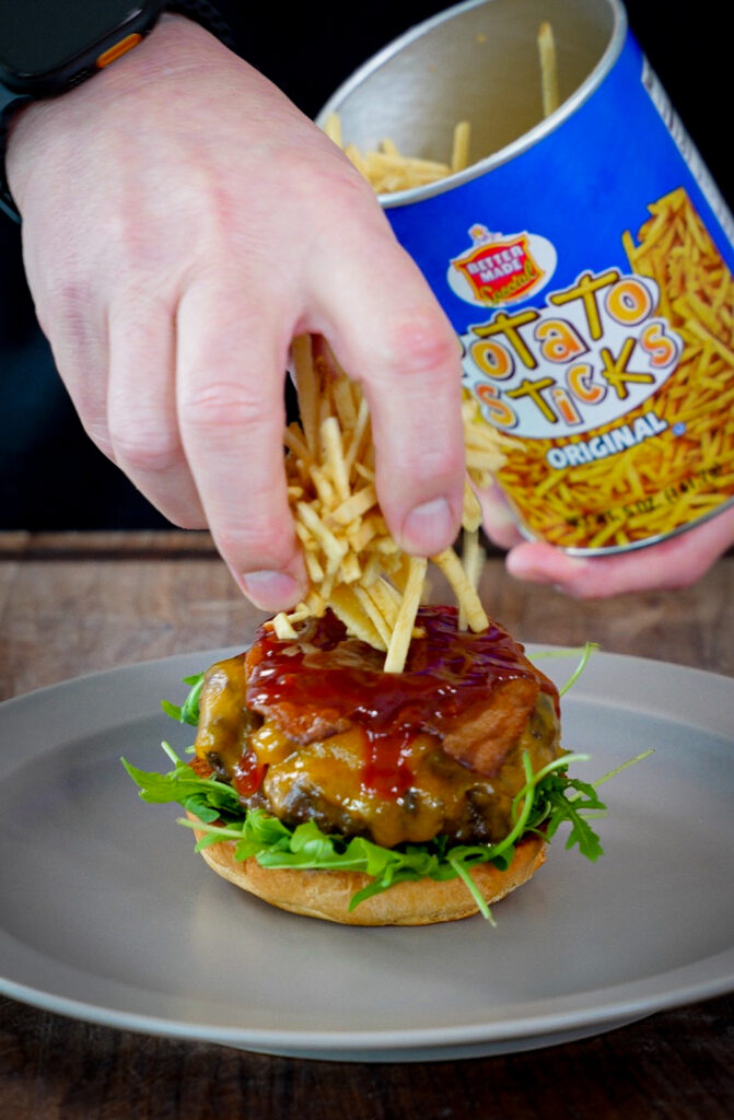shoe string potatoes being added to an Up North burger