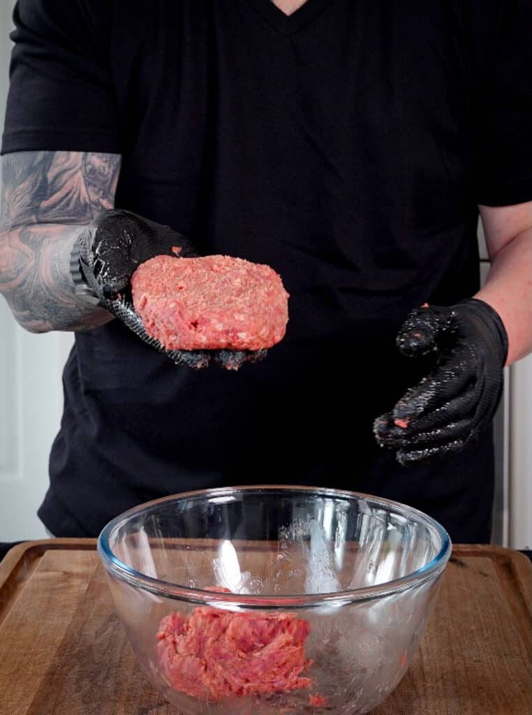 venison patty in a black gloved hand