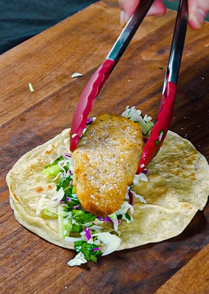 chicken tender being added to a taco