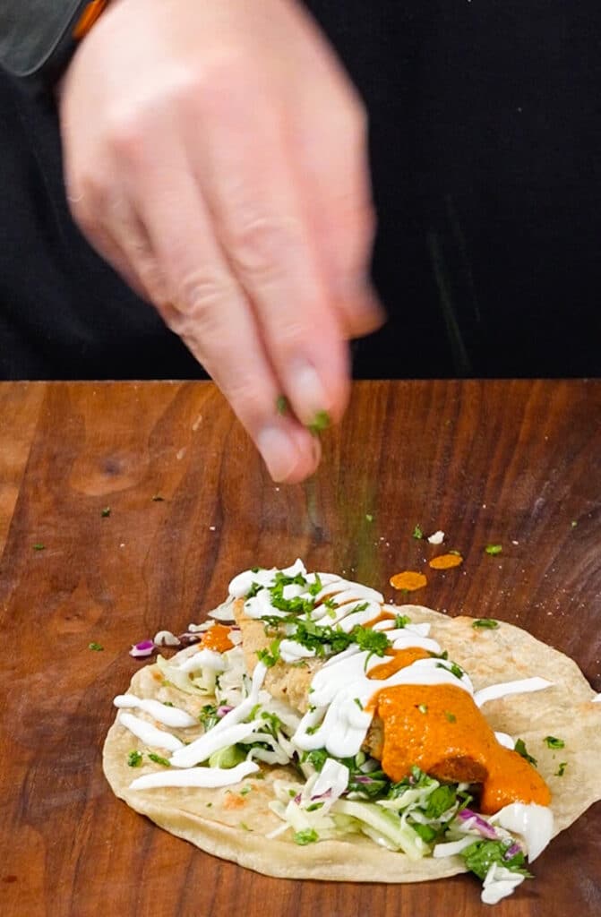cilantro being added to a taco
