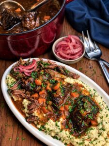 smoked braised short ribs on a platter with mashed potatoes and red onions